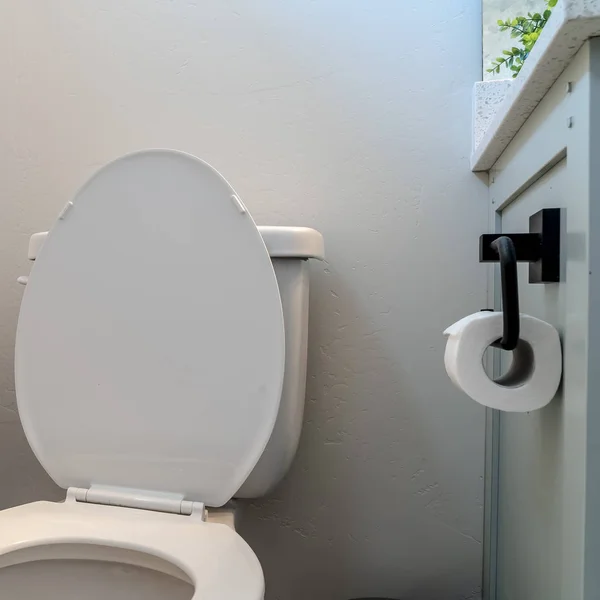Kwadratowa toaleta w łazience z uchwytem na bułeczki na śmieci i białą ścianą — Zdjęcie stockowe