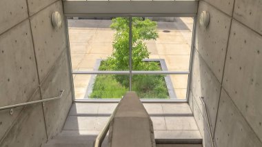 Panorama çerçeve. Camdan çatı altında metal korkuluklu merdiven uçuşu.