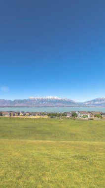 Dikey çerçeve golf sahası canlı yeşil otlarla kaplıydı. Evlere ve göle bakıyordu.