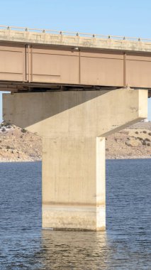 Dikey çerçeve Köprü ve iskele temeli mavi göl suyu üzerinde dağ ve mavi gökyüzüne karşı