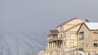 Panorama Evleri, karlı çatıları ve dağ ve gökyüzü arka planına karşı yardaları olan bir tepede.