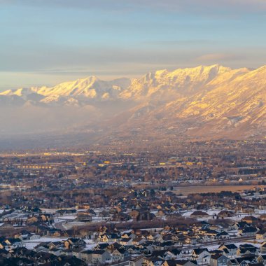 Fotoğraf Meydanı çerçeveli Karlı Timpanogos Dağı gün batımında altın güneş ışığıyla aydınlatılıyor