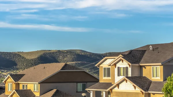 Panorama frame Houses with view of the roofs and upper storey against hills and vibrant sky — Stok fotoğraf