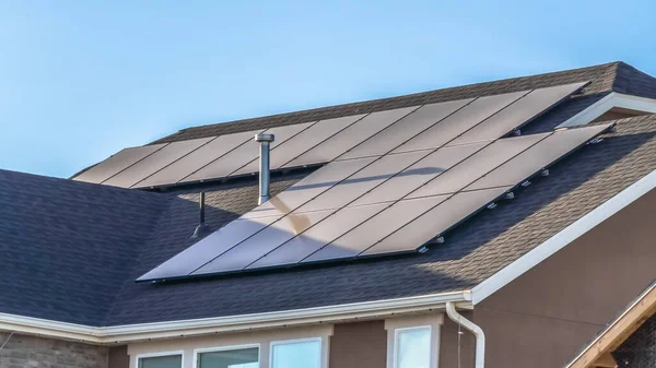 Panorama Gray roof of home with solar panels and pipe vents against blue sky background — Stok fotoğraf