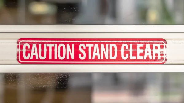 Panorama Cuidado Stand Sinal claro na placa de metal da porta de vidro de um edifício — Fotografia de Stock