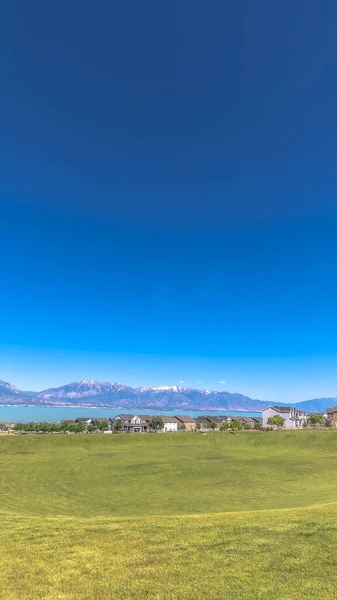 Vertikální rám Scénický pohled na horské domy u jezera a nebe s golfovým hřištěm v popředí — Stock fotografie