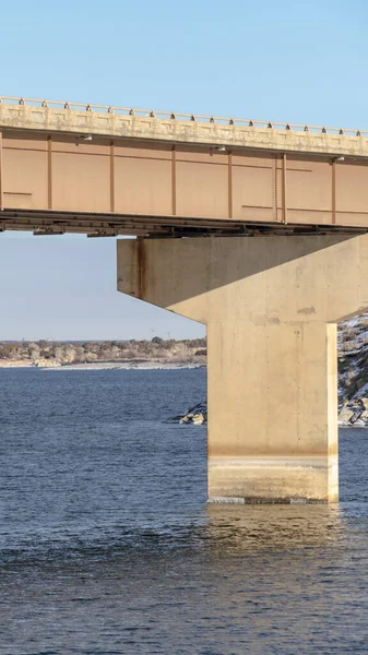 Вертикальный фокус на лучевом мосту, поддерживаемом опорами над голубым озером против облачного неба — стоковое фото