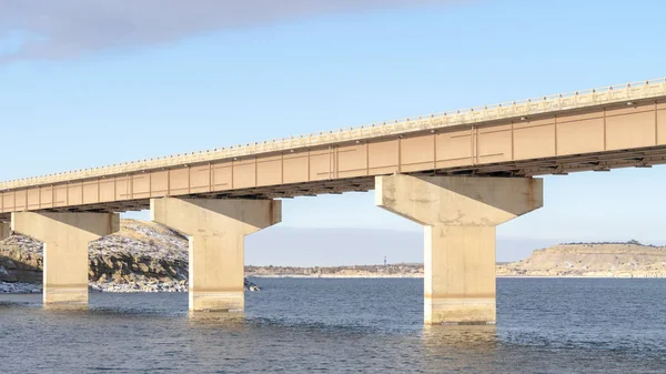 Panorama Stringer köprüsü mavi bir gölün üzerinden geçiyor ve karlı kayalık arazileri birbirine bağlıyor
