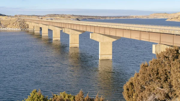 Panorama Blauer See mit Brücke, die riesige, im Winter schneebedeckte Flächen verbindet — Stockfoto