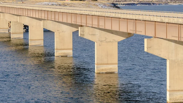 Panorama Stringer Brücke über ruhigen See mit Blick auf verschneites Land und wolkenverhangenen Himmel — Stockfoto