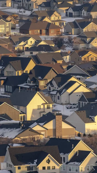 Foto Vertikaler Rahmen Häuser mit schneebedeckten Dächern und verschneiten Höfen, die im Winter vom Sonnenlicht beleuchtet werden — Stockfoto