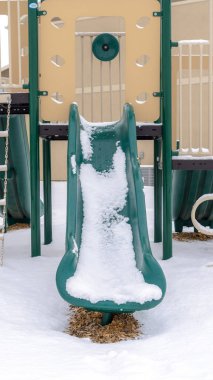 Çocuk parkında kışın karla kaplı zemine karşı dikey yeşil kayar