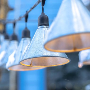 Kare çerçeve Koni şekilli lambalar siyah elektrik telleri üzerinde asılı bulanık gökyüzüne karşı