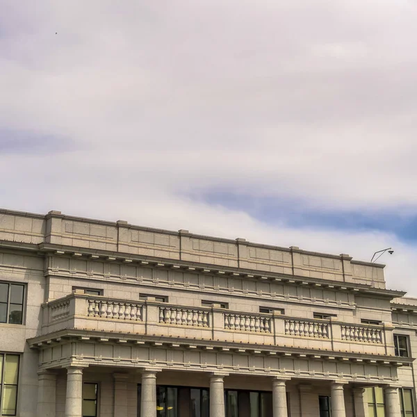 Kvadratram Molnigt blå himmel över byggnad med balkong och stora kolumner vid ingången — Stockfoto