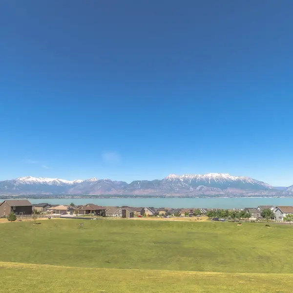Campo de golf cuadrado cubierto con hierbas verdes vibrantes con vistas a las casas y el lago —  Fotos de Stock