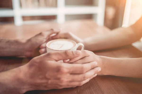 Couple holding hands with coffee — Stock Photo, Image
