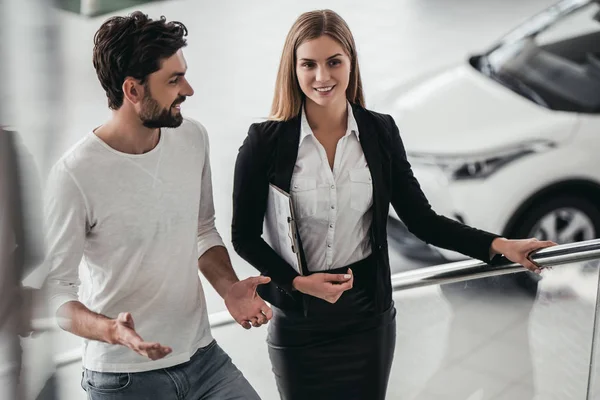 Vendedor con cliente en concesionario de coches — Foto de Stock