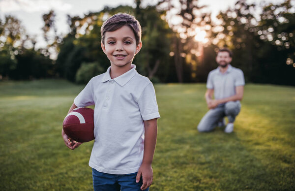 Папа с сыном играют в американский футбол
