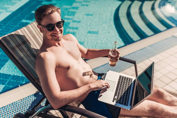 Man with laptop near swimming pool