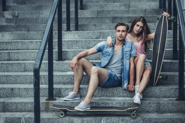 Casal de adolescentes com skates na cidade — Fotografia de Stock