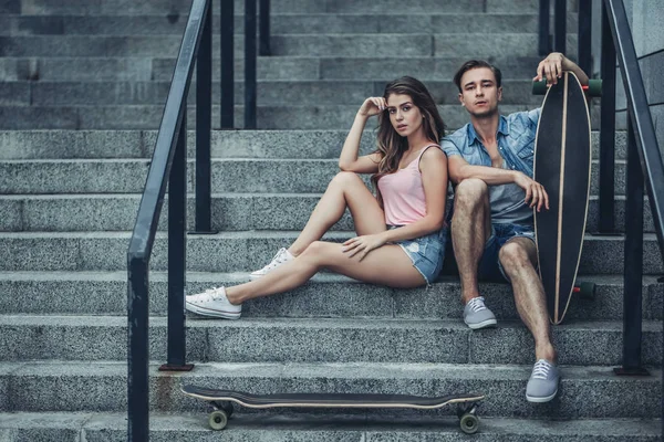 Casal de adolescentes com skates na cidade — Fotografia de Stock