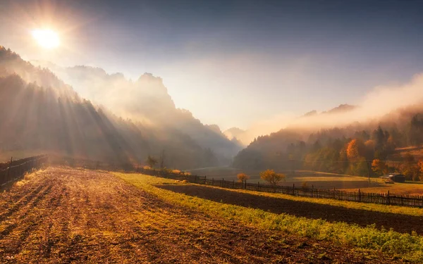 Raggi di sole attraverso la nebbia mattutina nel paesaggio montano . — Foto Stock
