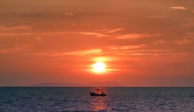Günbatımında sakin denizde balıkçı.