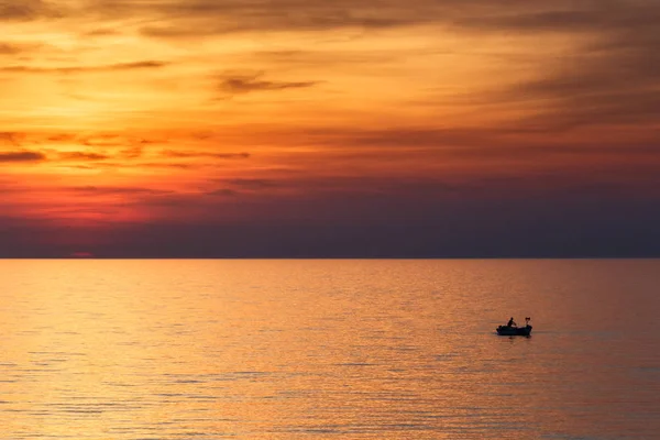Een visser zeilen op de zee bij zonsondergang. — Stockfoto