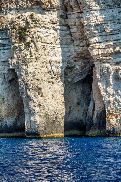 Acantilados empinados con cuevas marinas en la costa de la isla de Paxos . — Foto de Stock