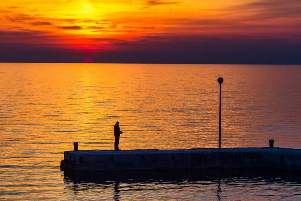 Solnedgång med siluett av fiskare till havs. — Stockfoto