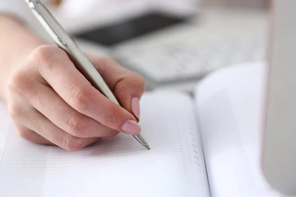 Vrouwelijke hand met zilveren pen klaar om notitie te maken — Stockfoto