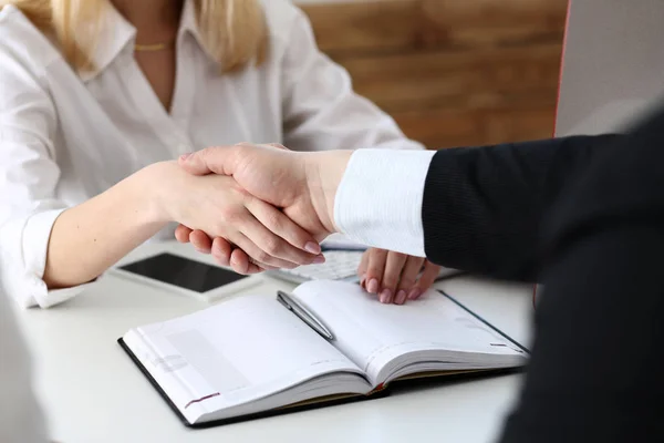 Businessman and woman shake hands as hello in office