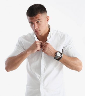 Bir adam beyaz gömleğin yakasını düzeltir.