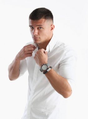 Bir adam beyaz gömleğin yakasını düzeltir.