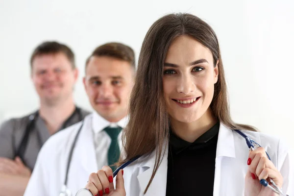 Grupo de médicos posando orgullosamente en fila y mirando a la cámara —  Fotos de Stock