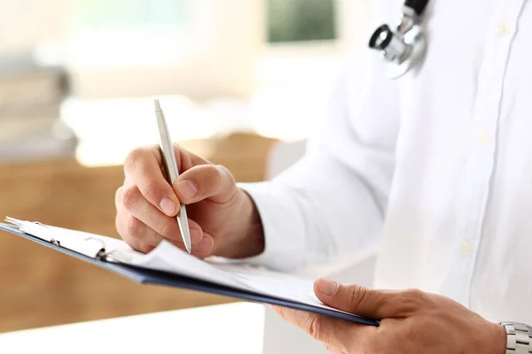 Médico masculino mano sosteniendo pluma de plata y portapapeles — Foto de Stock