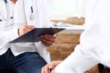 Erkek tıp doktor Pano defterinde el ile incelemek hasta