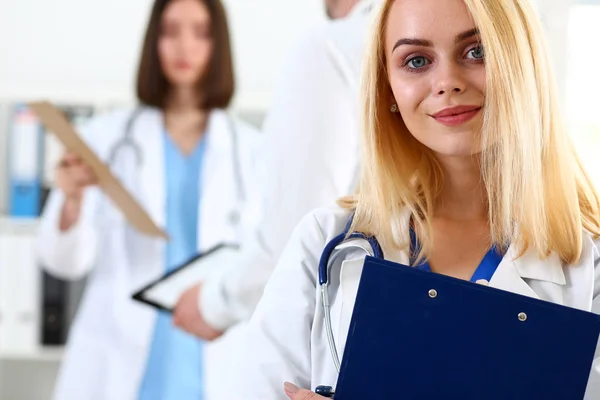 Schöne lächelnde Ärztin hält und umarmt Klemmbrett-Pad — Stockfoto