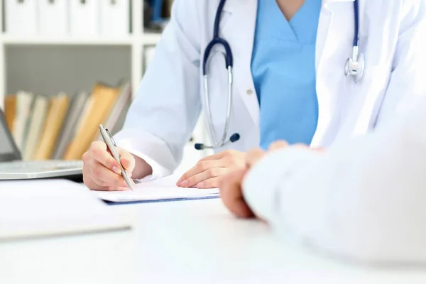 Lekarka ręka trzymać srebrne pióro wypełnienie listy pacjentów — Zdjęcie stockowe