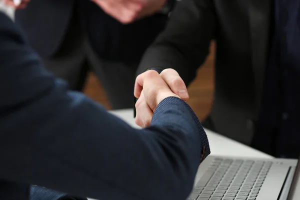Two businessman shake hands as hello in office closeup