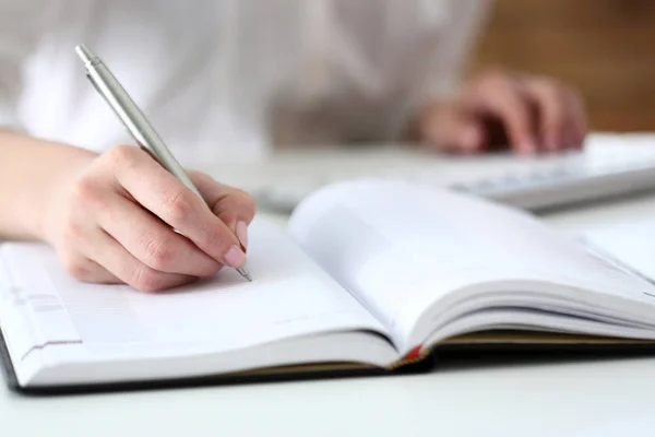 Female hand holding silver pen ready to make note — Stock Photo, Image