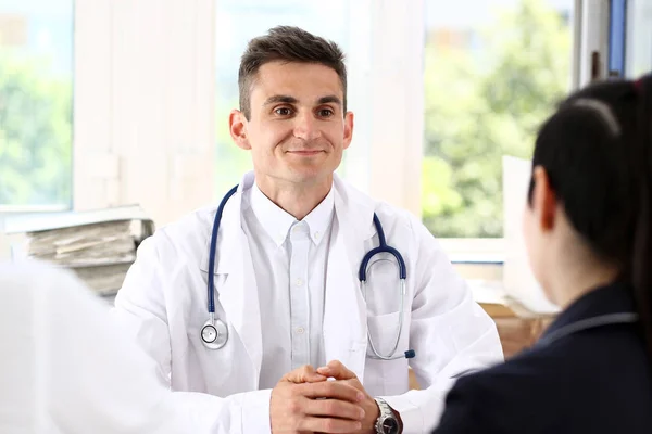 Male family doctor listen carefully young couple in office