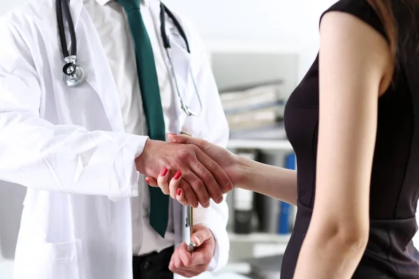 Doctor shake hand as hello with patient in office closeup