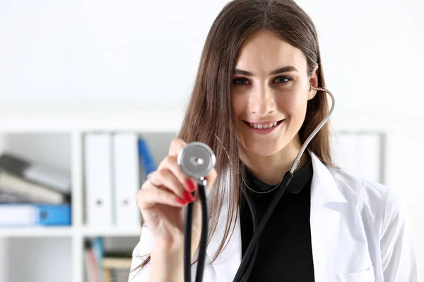 Hermosa mujer sonriente médico en la mano estetoscopio cabeza —  Fotos de Stock