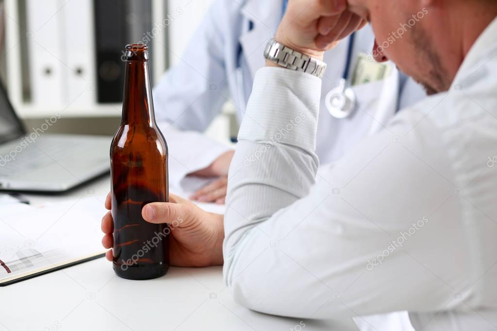 Alcoholic hold in hand empty bottle at doctor reception