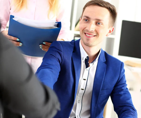 Улыбающийся мужчина в костюме пожимает руку в знак приветствия в офисе — стоковое фото