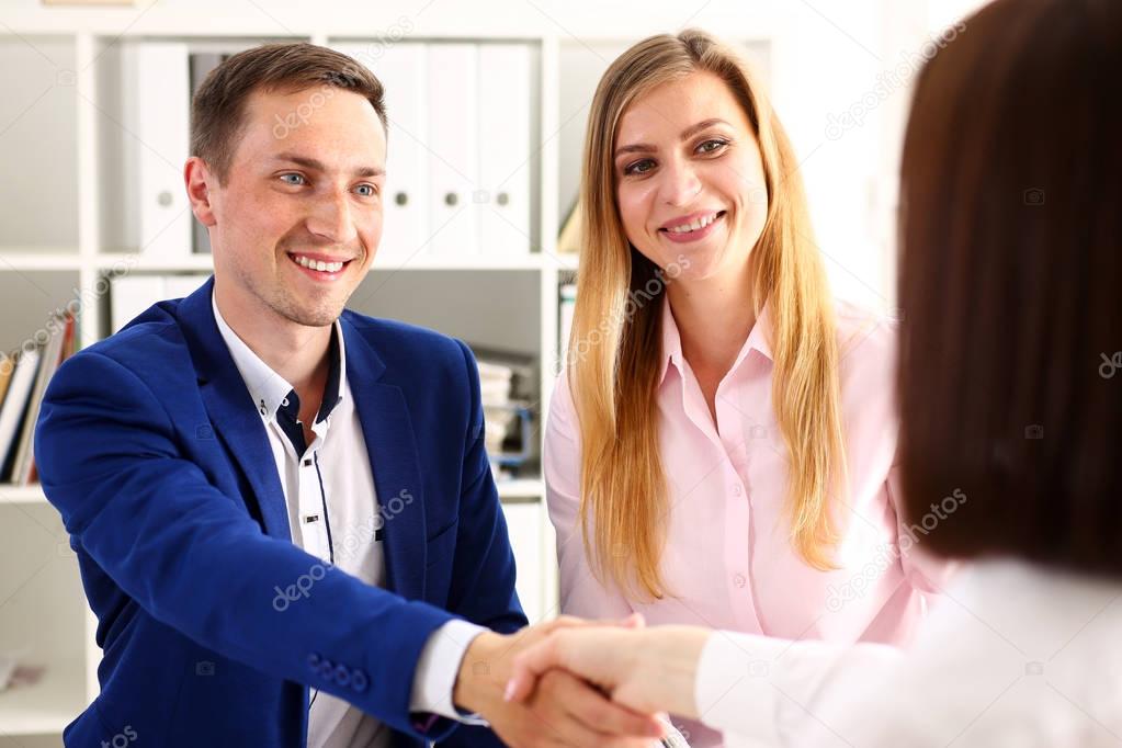 Smiling man and woman shake hands as hello in office