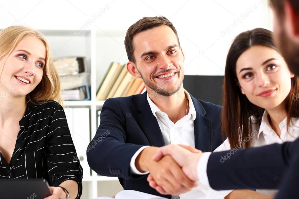 Smiling man in suit shake hands as hello in office
