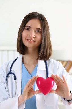 Kadın tıp doktor eller kırmızı oyuncak kalbinde tutun 
