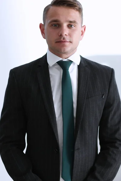 Przystojny człowiek uśmiechający się w garnitur i krawat stoją w biurze — Zdjęcie stockowe